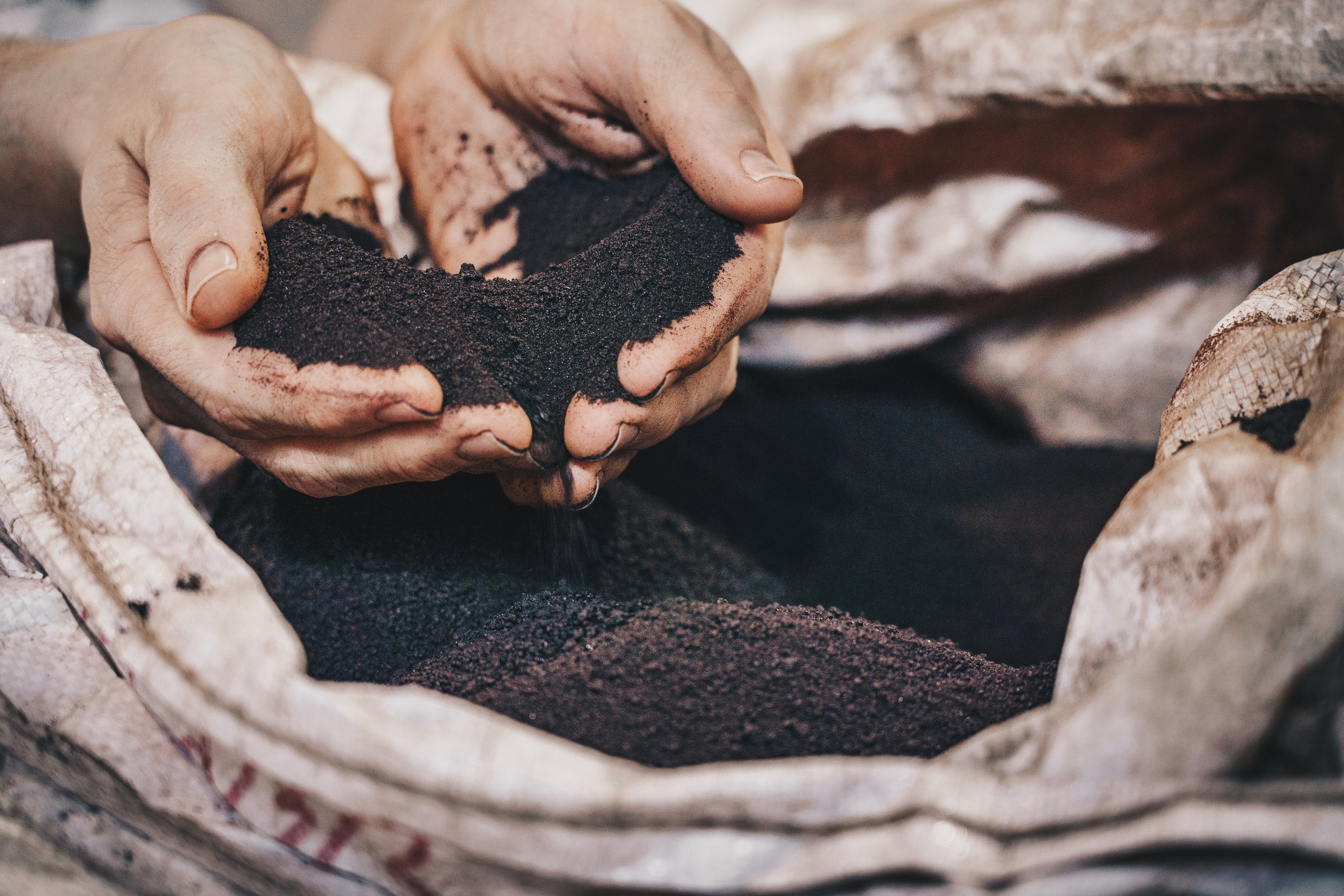 Nahaufnahme von Händen, die RETENTIS®-Wasserspeichergel von Agrobiogel aus einem großen Sack schöpfen.